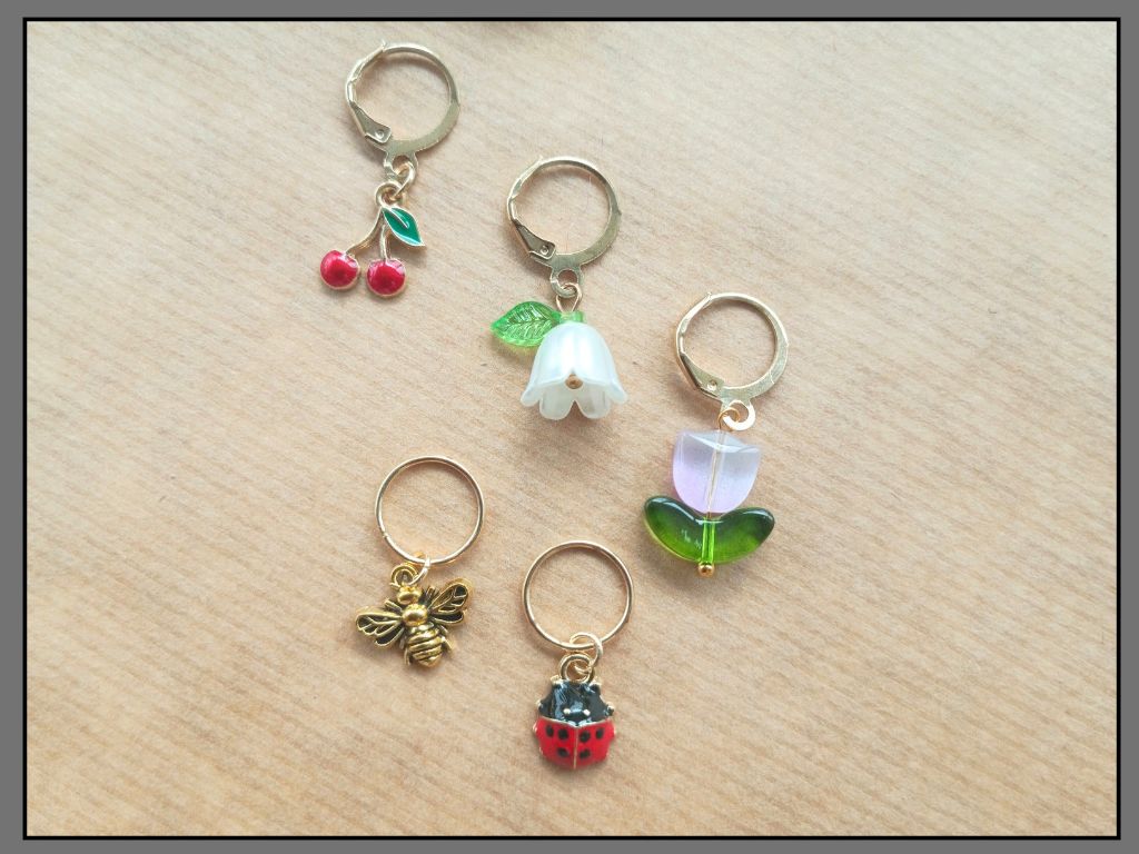 Stitch marker set with flower, cherry, ladybug and bee pendants for knitting and crochet projects. 