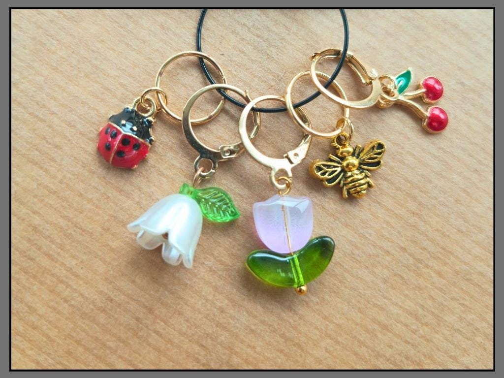 Stitch marker set with flower, cherry, ladybug and bee pendants for knitting and crochet projects. 