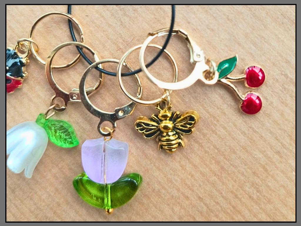 Stitch marker set with flower, cherry, ladybug and bee pendants for knitting and crochet projects. 